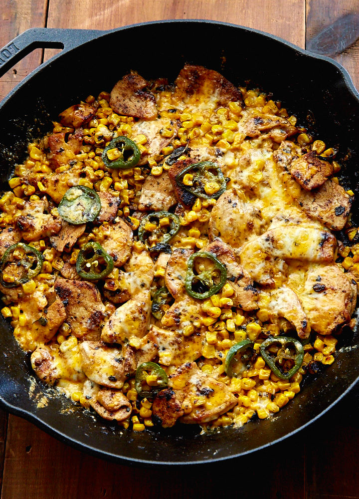 Close up of Mexican Chicken with Corn, Chilies and Cheese in a black pan.