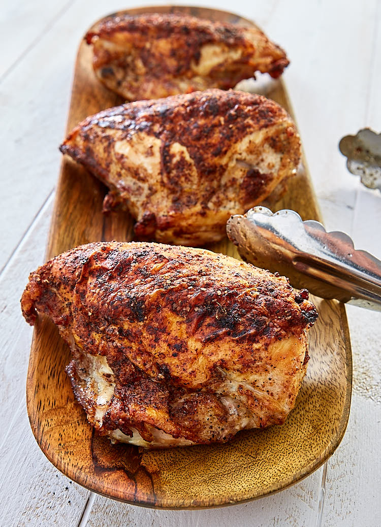 Crispy pan fried, baked chicken breasts on a wooden tray.