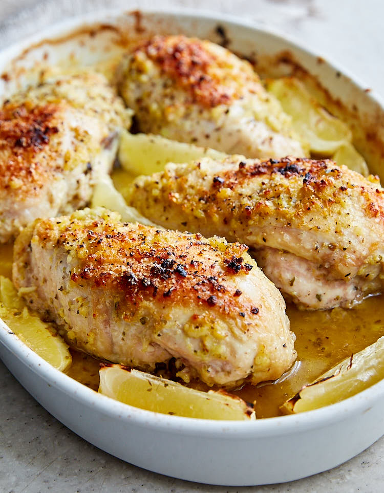 Baked chicken with lime wedges in a baking pan.