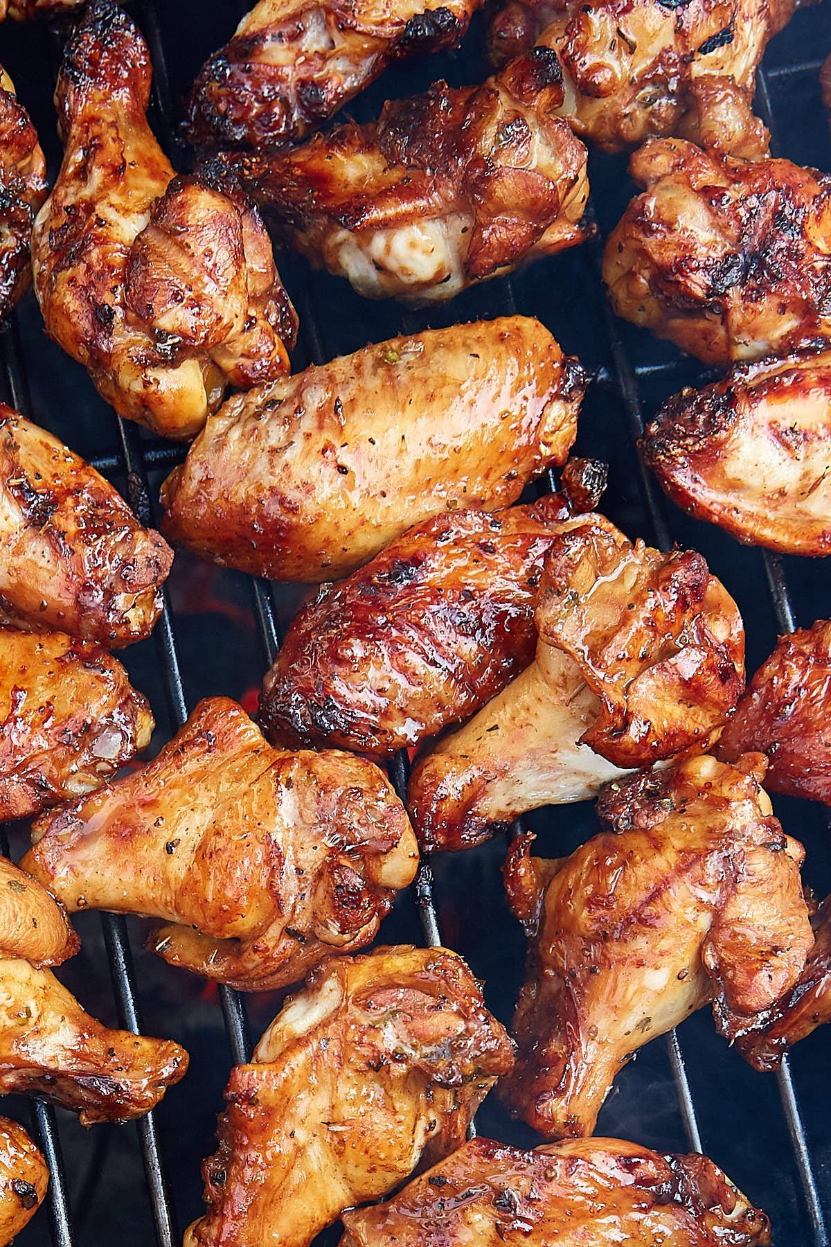 Chicken wings grilling on a grill over hot red charcoal.