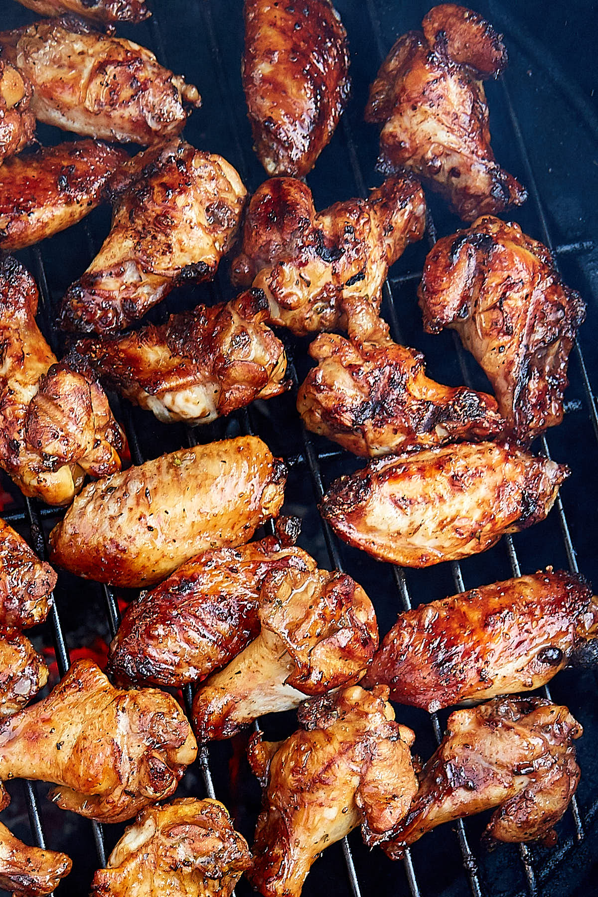 Crispy browned charcoal grilled chicken wings on a rack over hot charcoal.