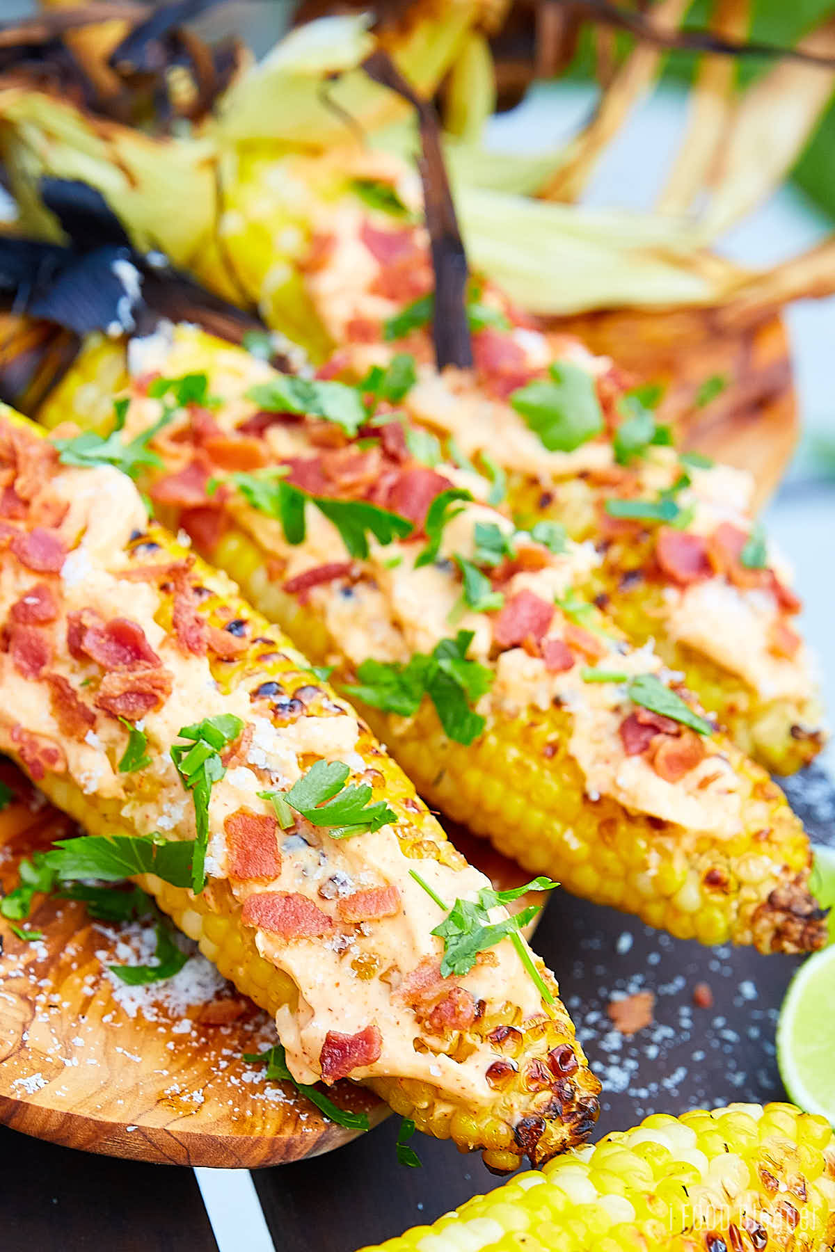 Grilled corn on the cob, smothered with mayo and topped with bacon and parsley.