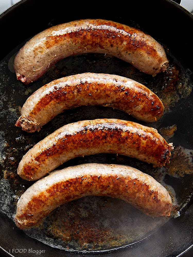 Top down view of four brats in a cast iron pan.