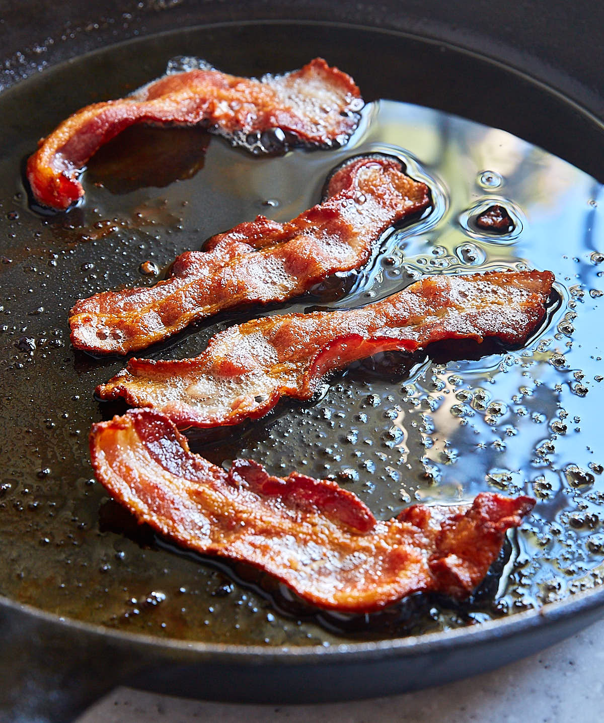 Fried bacon strips in a cast iron pan.