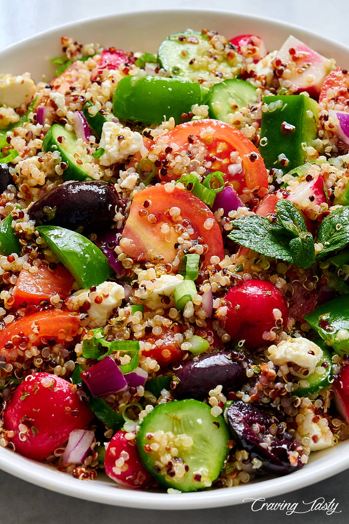 Close up of zesty quinoa salad in a white bowl.