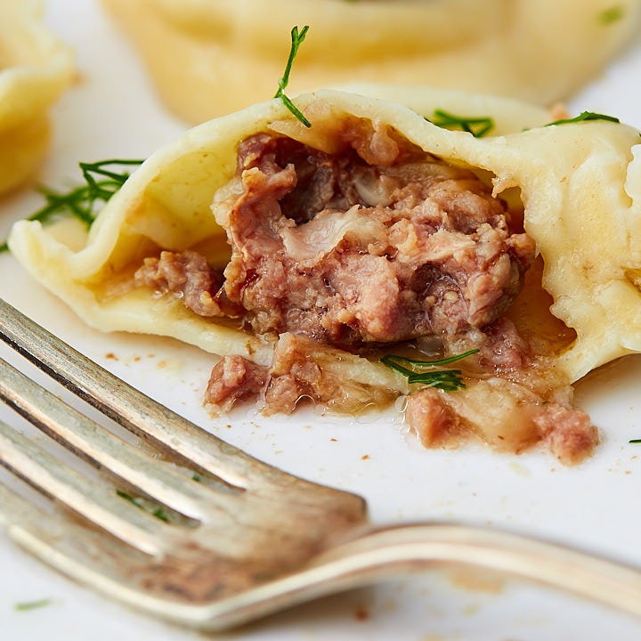 A close up of a split pelmeni showing very juicy meat inside.