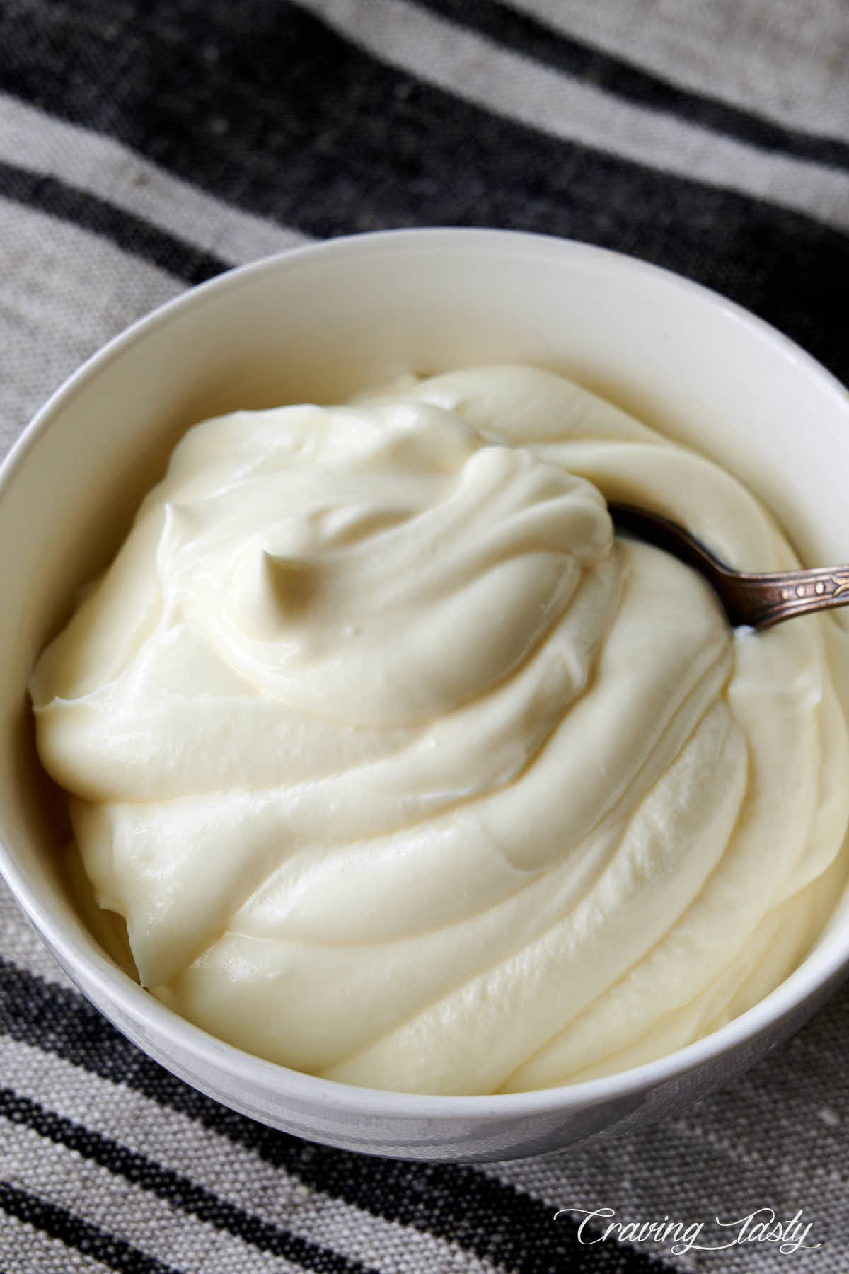 Creme fraiche in a white bowl with a spoon.