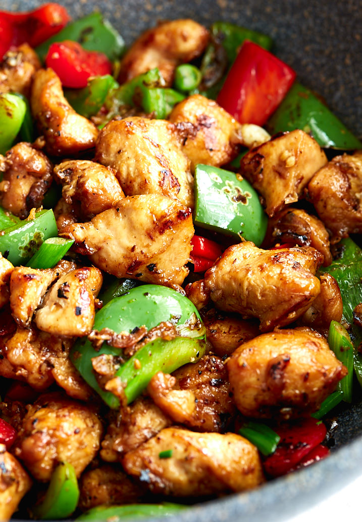 Szechuan chicken with red and green bell peppers in a wok.