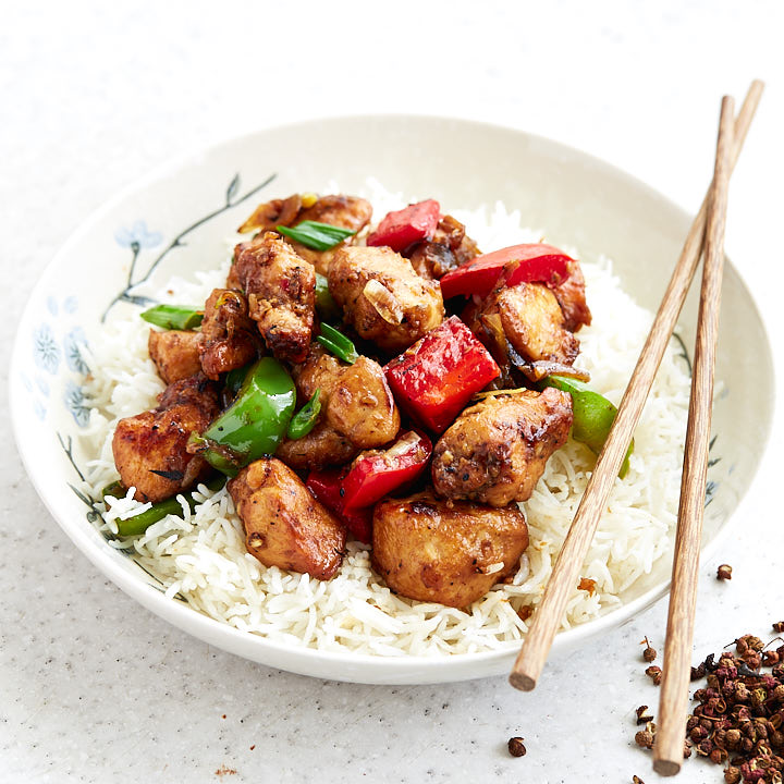 Szechuan chicken in a bowl with peppers over rice.