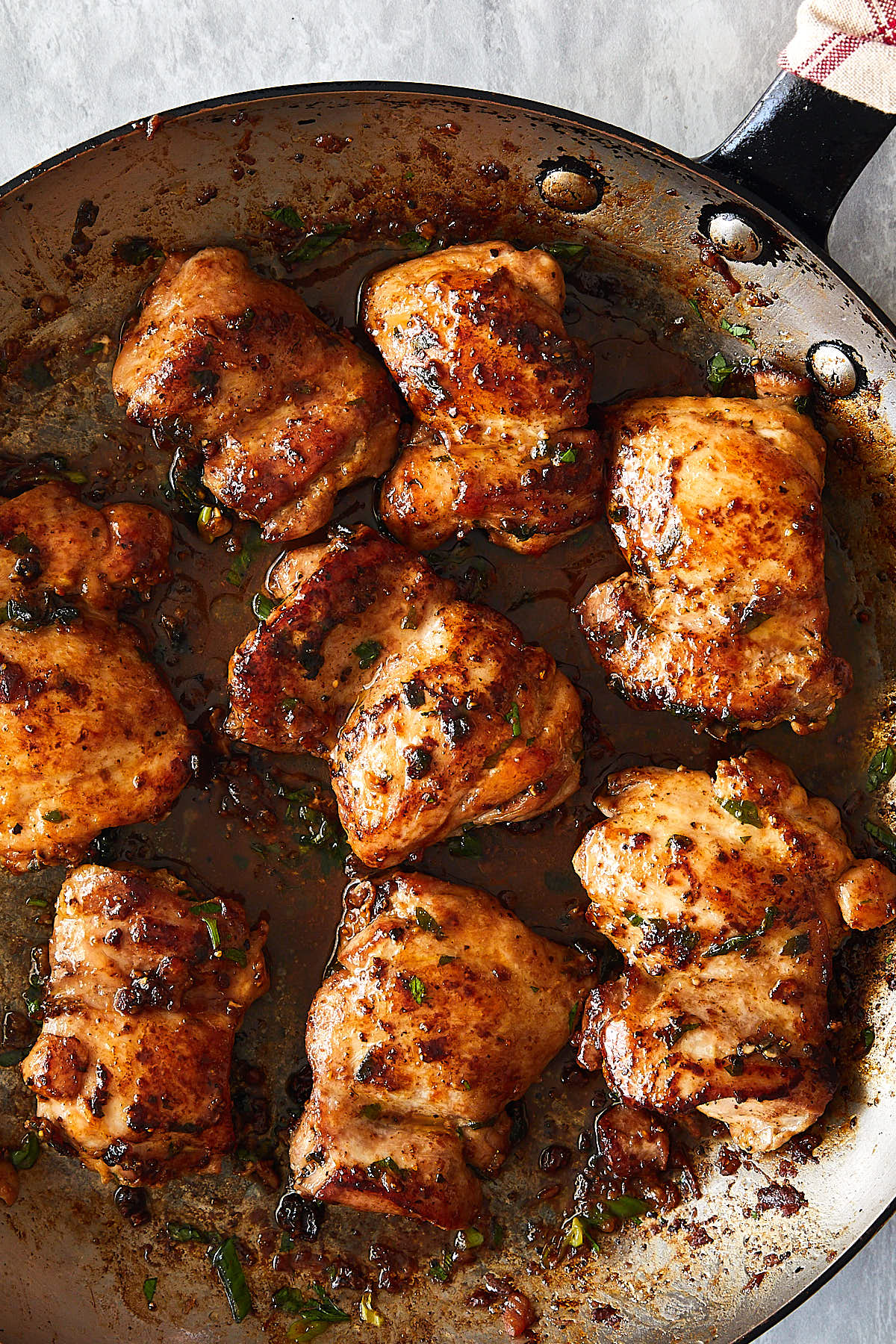 Close up of succulent, well-browned pan-fried chicken thighs in a skillet.