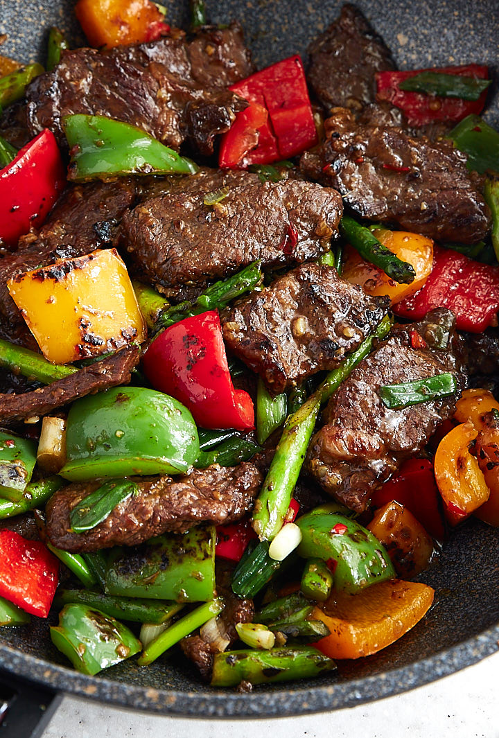 Hunana beef, well-browned, with vegetables in a wok.