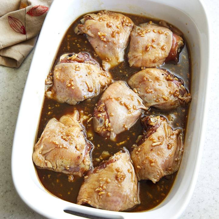 Chicken thighs inside a baking dish with marinade.