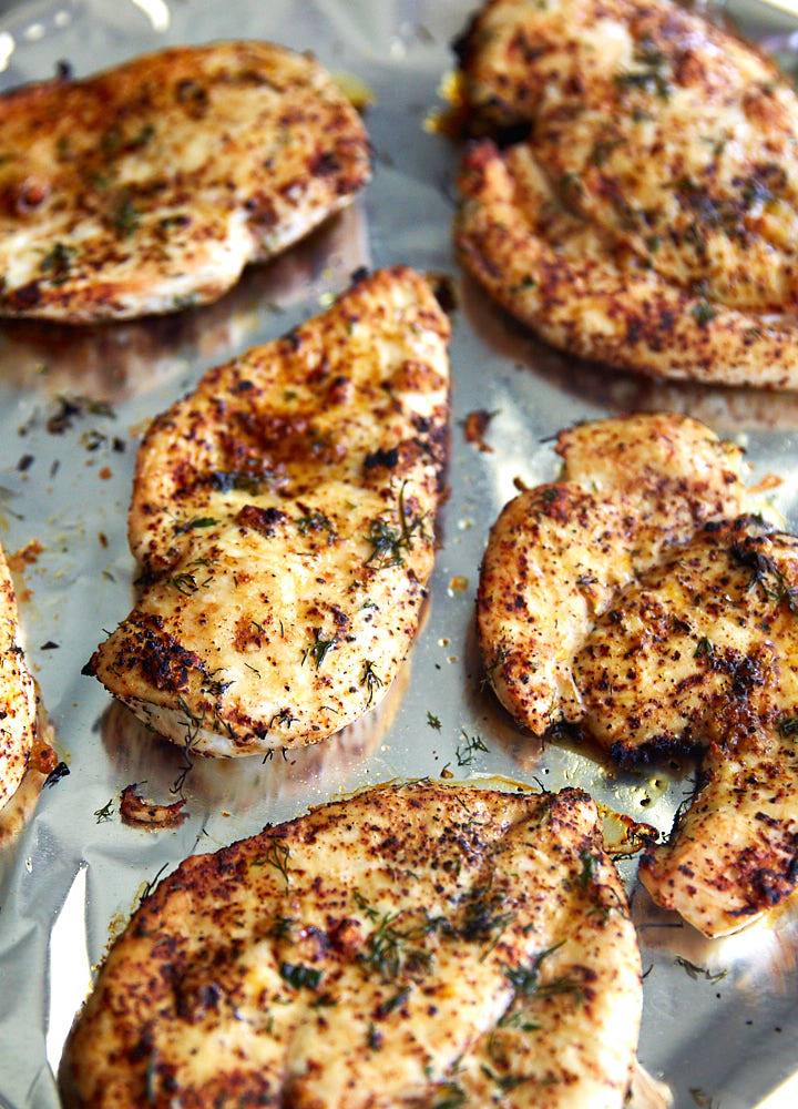 Broiled chicken breasts, nicely browned, on a baking tray.
