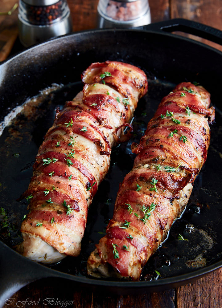 Bacon-wrapped pork tenderloins in a cast iron pan.