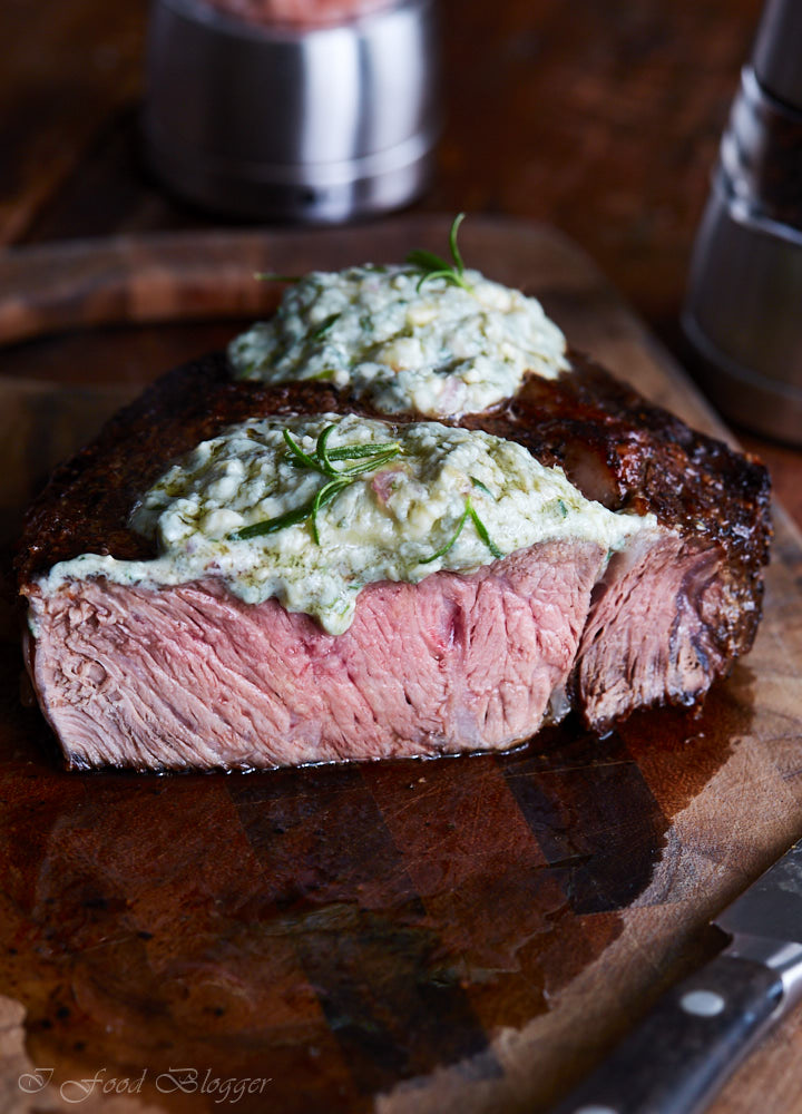 Pan-seared ribeye steak, finished in the oven for perfect doneness, then topped with blue cheese and shallot compound butter and fresh rosemary.