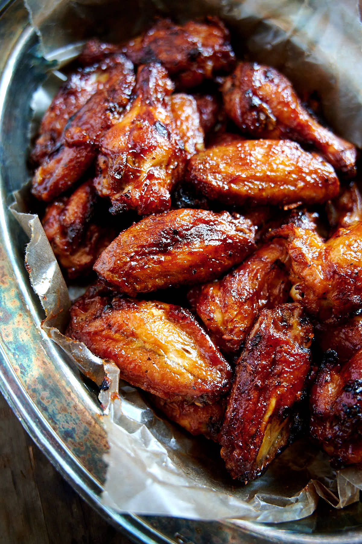 Bright red, crispy BBQ chicken wings in a serving basket.