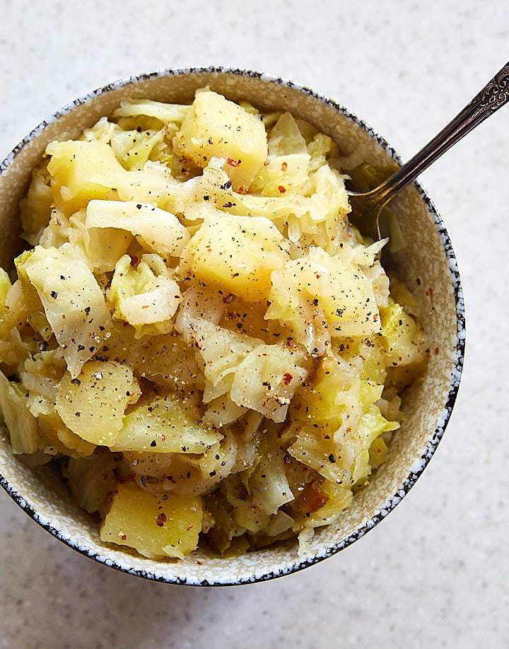 Top down view of a specked bowl full of smothered cabbage.