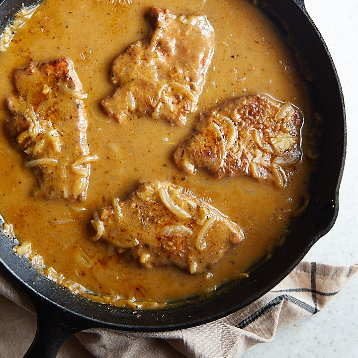 Smothered Pork Chops in a cast iron pan.