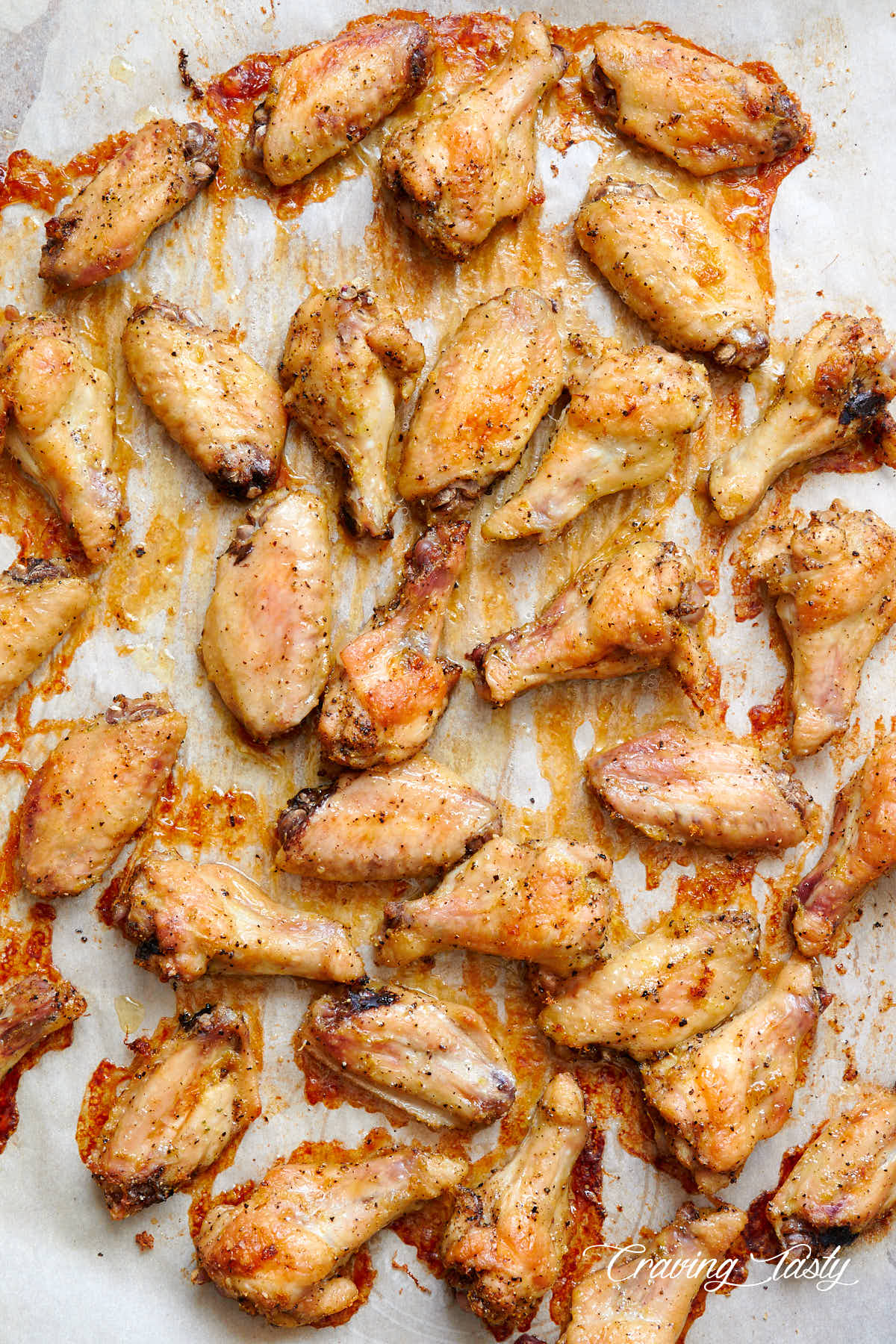 Lemon pepper chicken wings, fully baked, well-browned and crispy, on a baking tray lined with parchment paper.