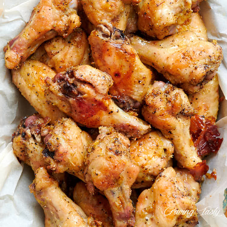 Chicken wings, seasoned with lemon and pepper, in a basket lined with wax paper