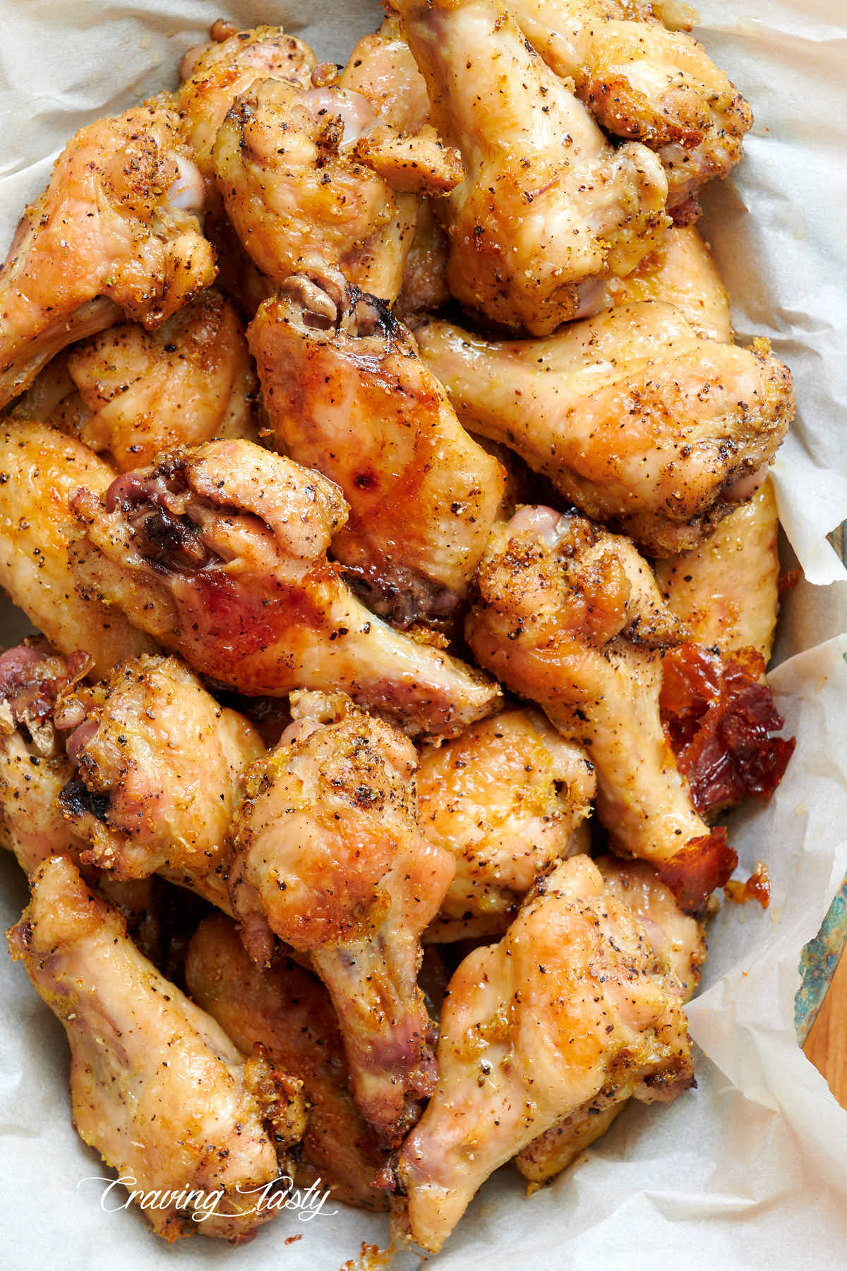 Chicken wings, seasoned with lemon and pepper, in a basket lined with wax paper