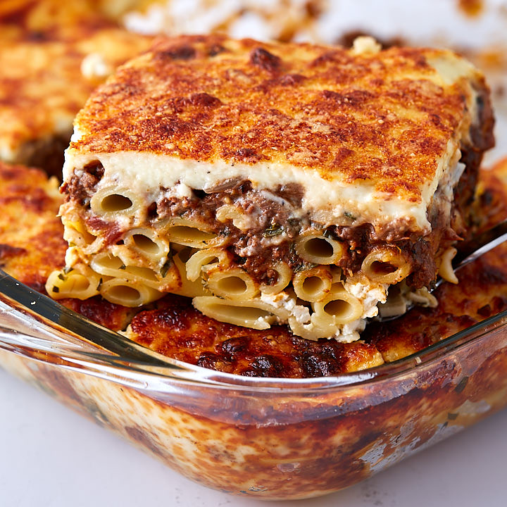 A close up of Greek lasagna slice showing ziti noodles, bechamel sauce and meat filling.