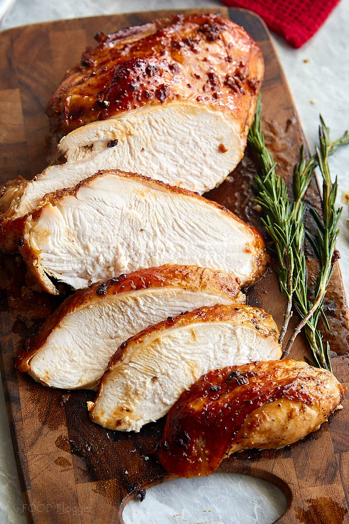 Sliced marinated turkey breast on a brown wooden cutting board.