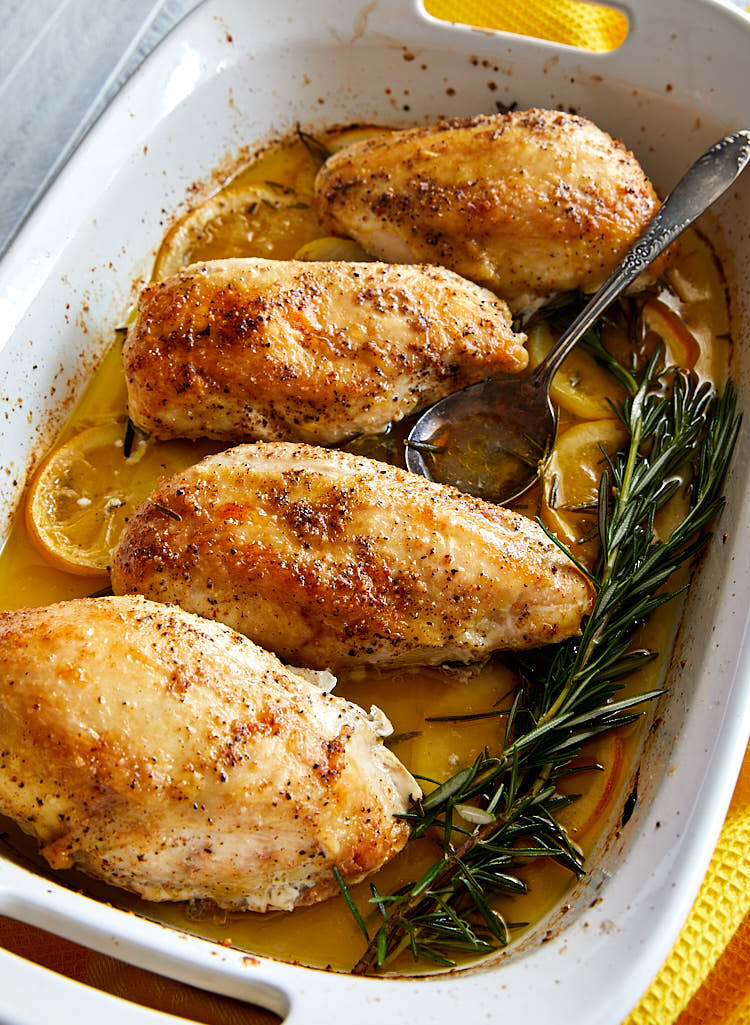 Close up of lemon and rosemary chicken in a baking dish.