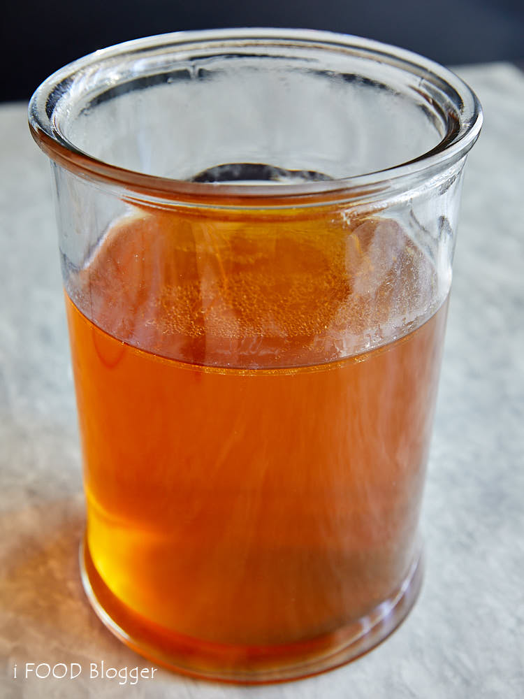 Clarified Beef Consomme in a tall wide glass jar.