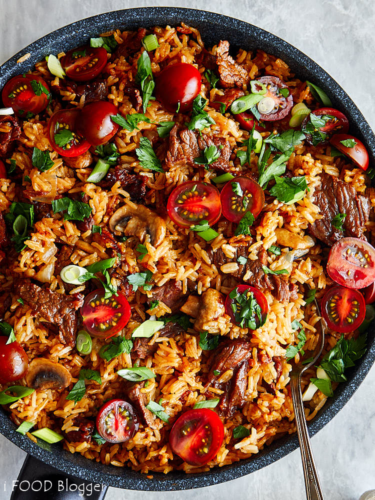 Top down view of a skillet full of beef fried rice garnished with chopped parsley.