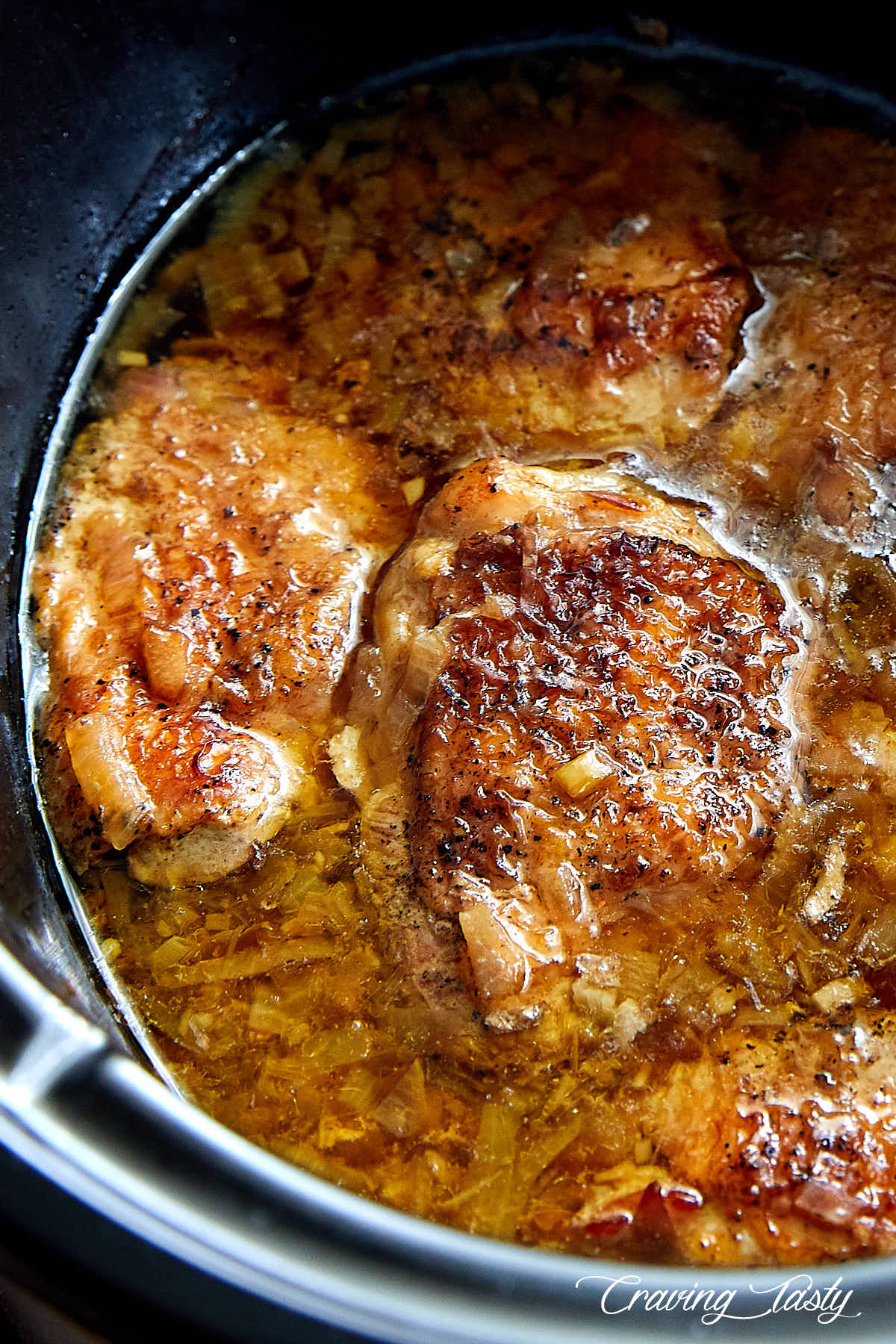 Close up of golden brown chicken in a slow cooker in juices.