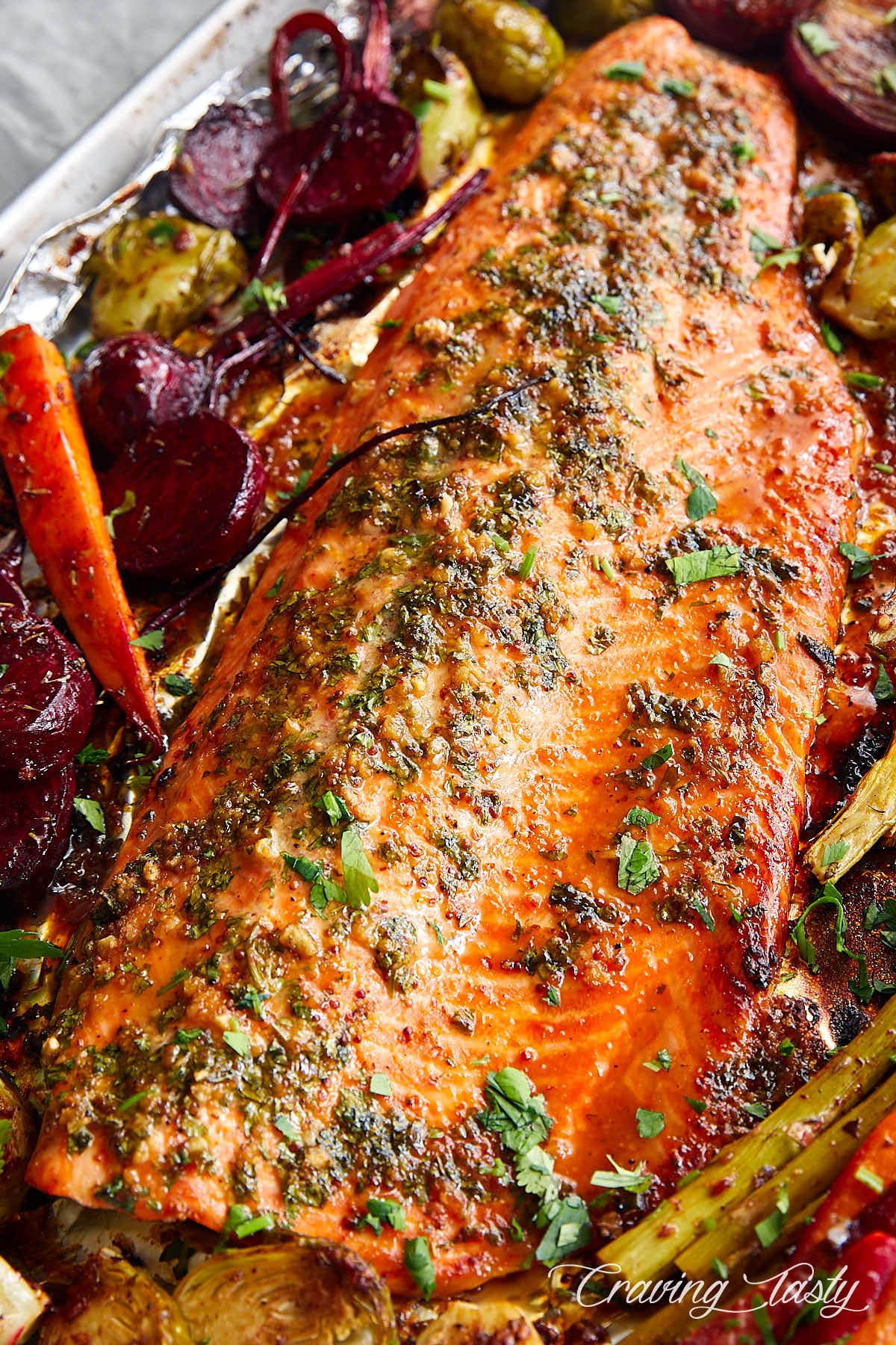 Steelhead trout filet on a piece of foil surrounded by roasted vegetables.