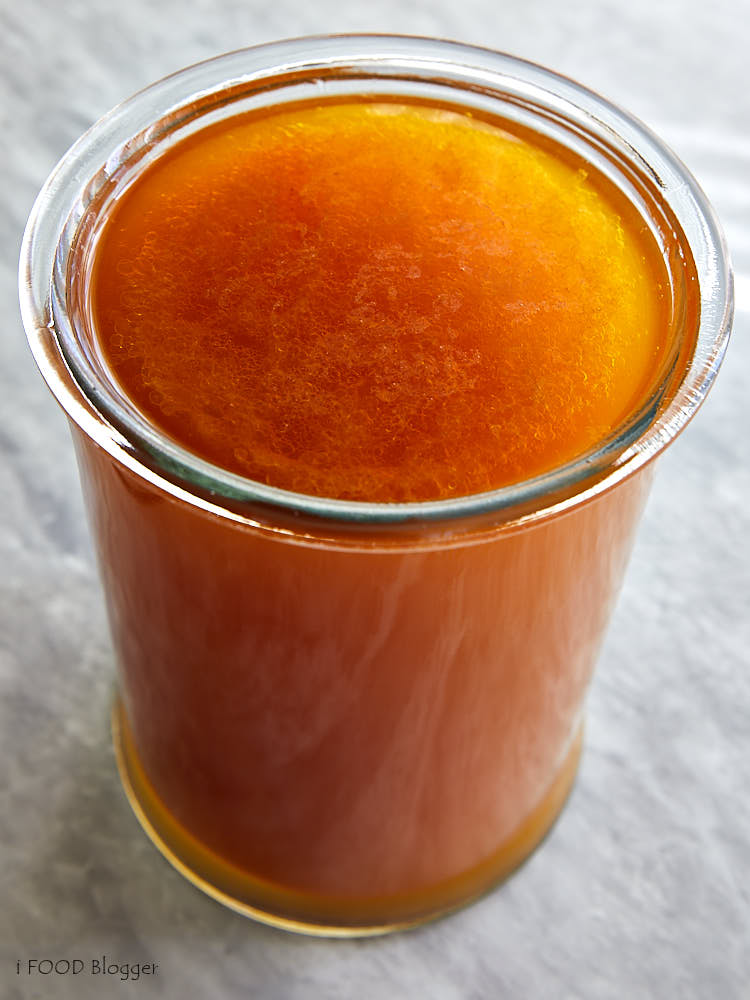 Amber color beef broth in a tall wide jar.