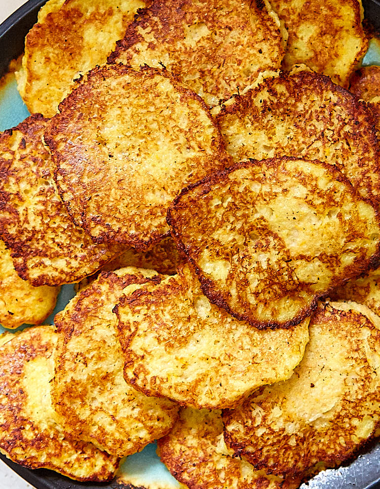 A close up of crispy, golden brown Polish potato pancakes on a platter.