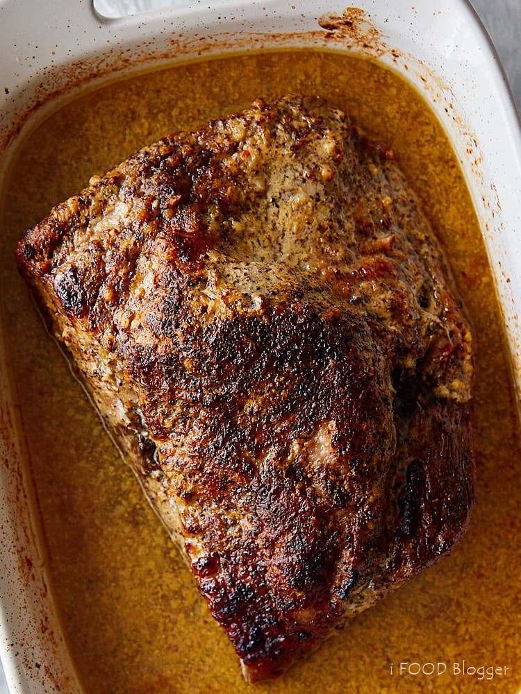 Oven-baked brisket in a white baking dish with juices.