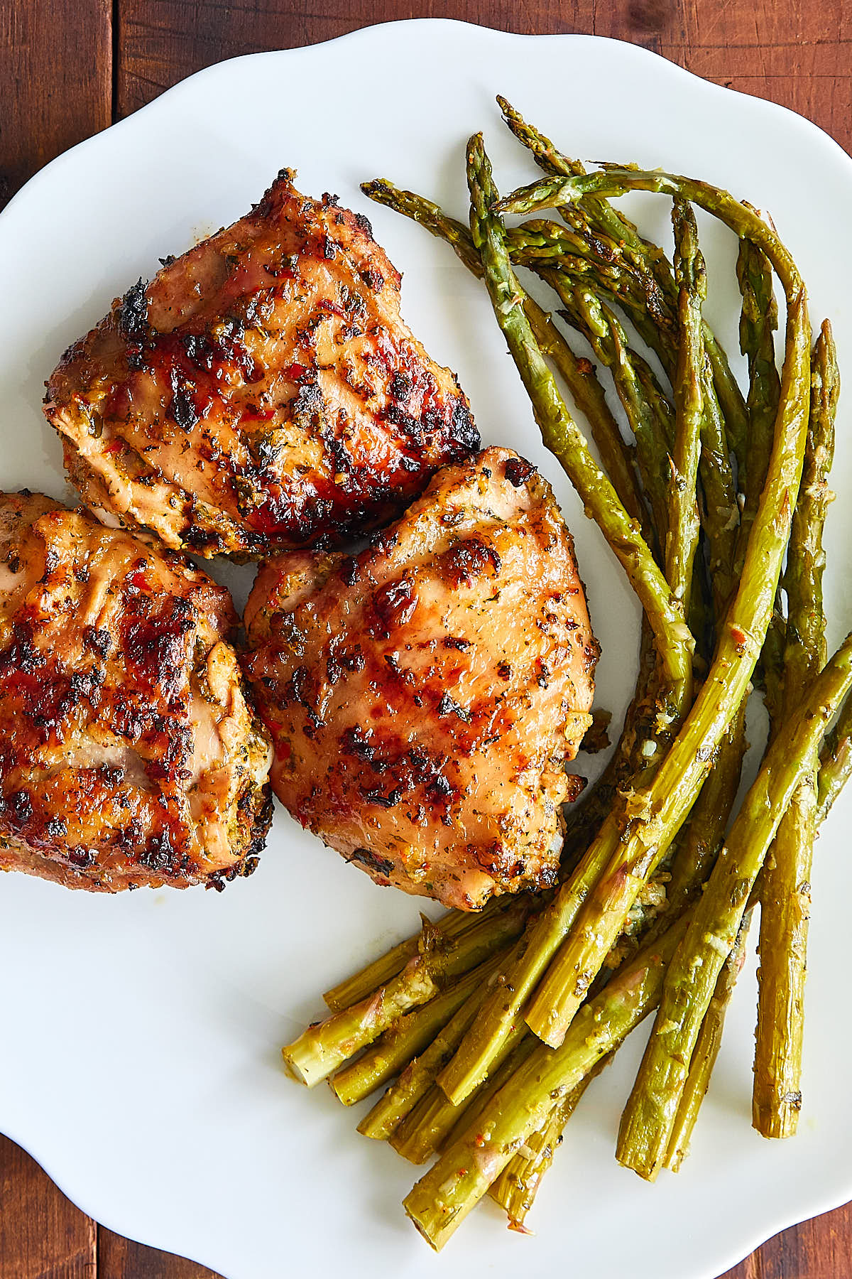 Grilled chicken thighs on a plate with asparagus.