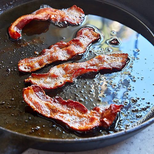 Fry bacon strips on a cast iron pan to render fat.