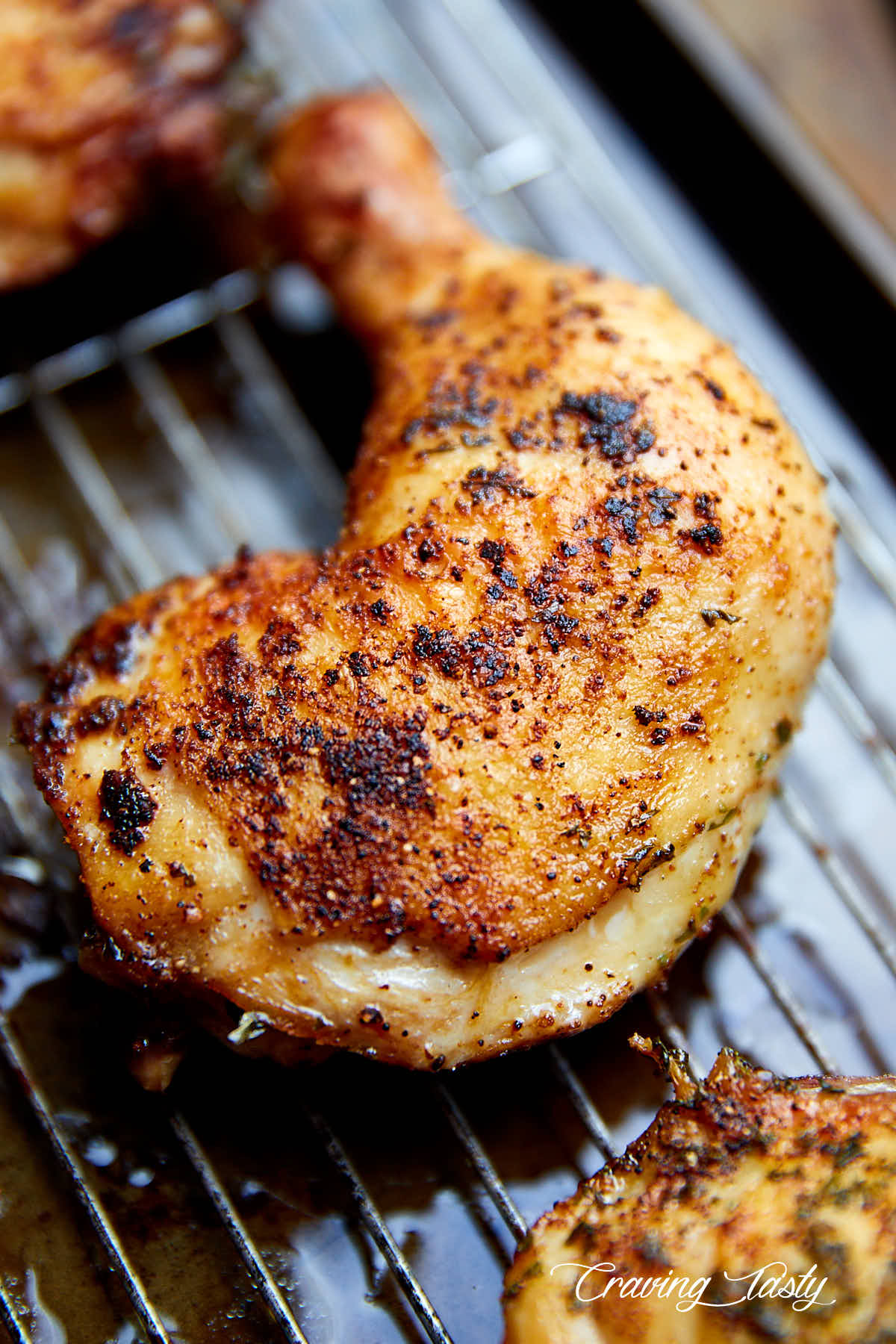 Crispy-skinned and fall-off-the-bone tender chicken quarter on a baking pan.