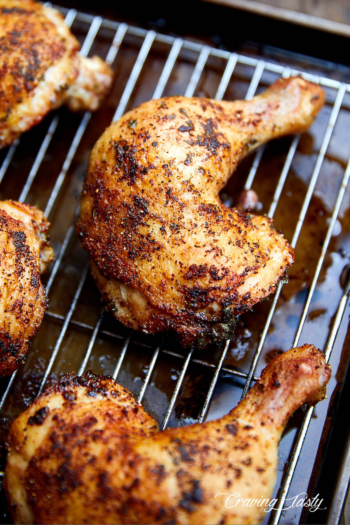 A close up view of a very crispy, browned chicken quarter on a baking dish fitted with a cooling rack.