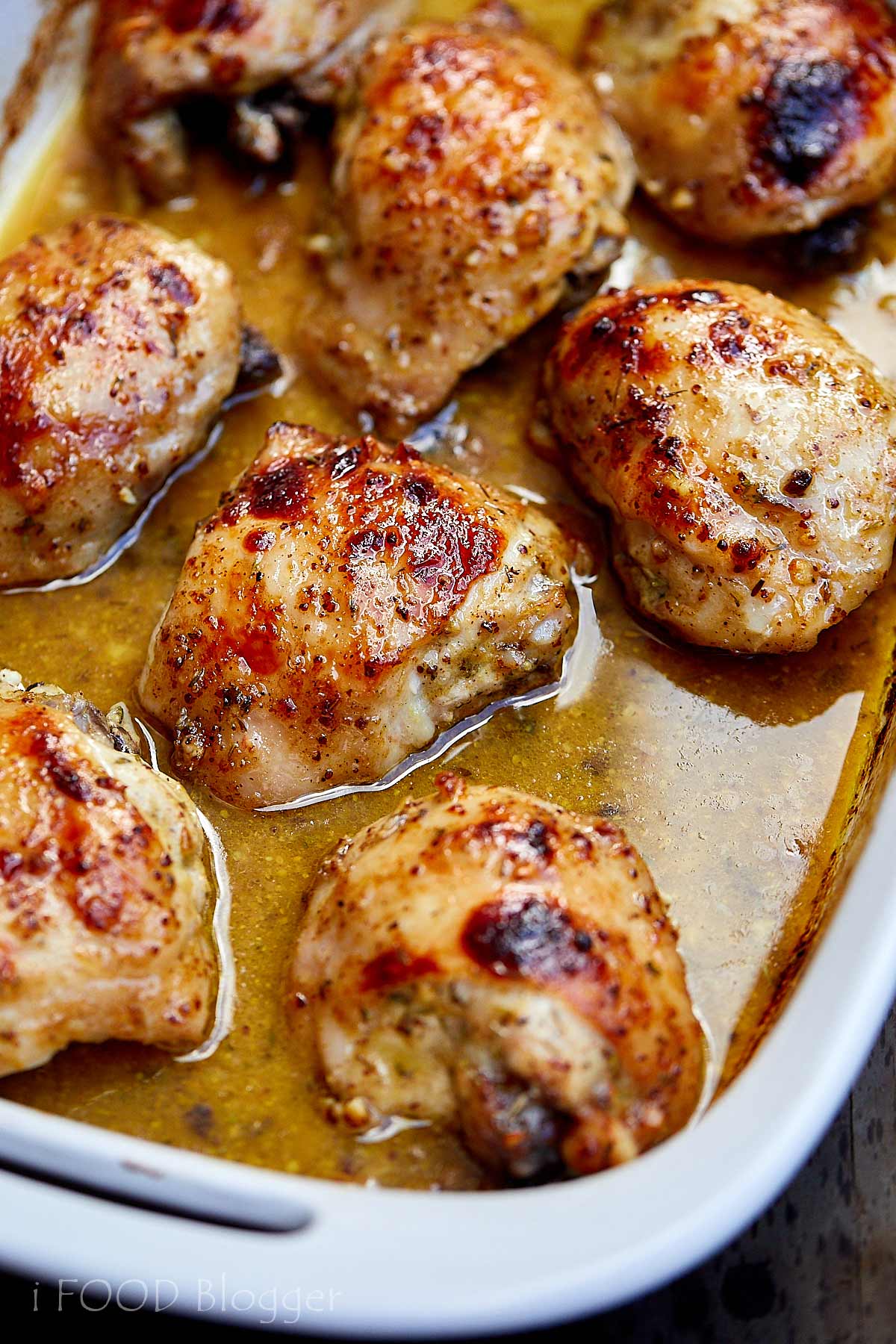 Nicely browned honey mustard chicken in white baking dish with juices.