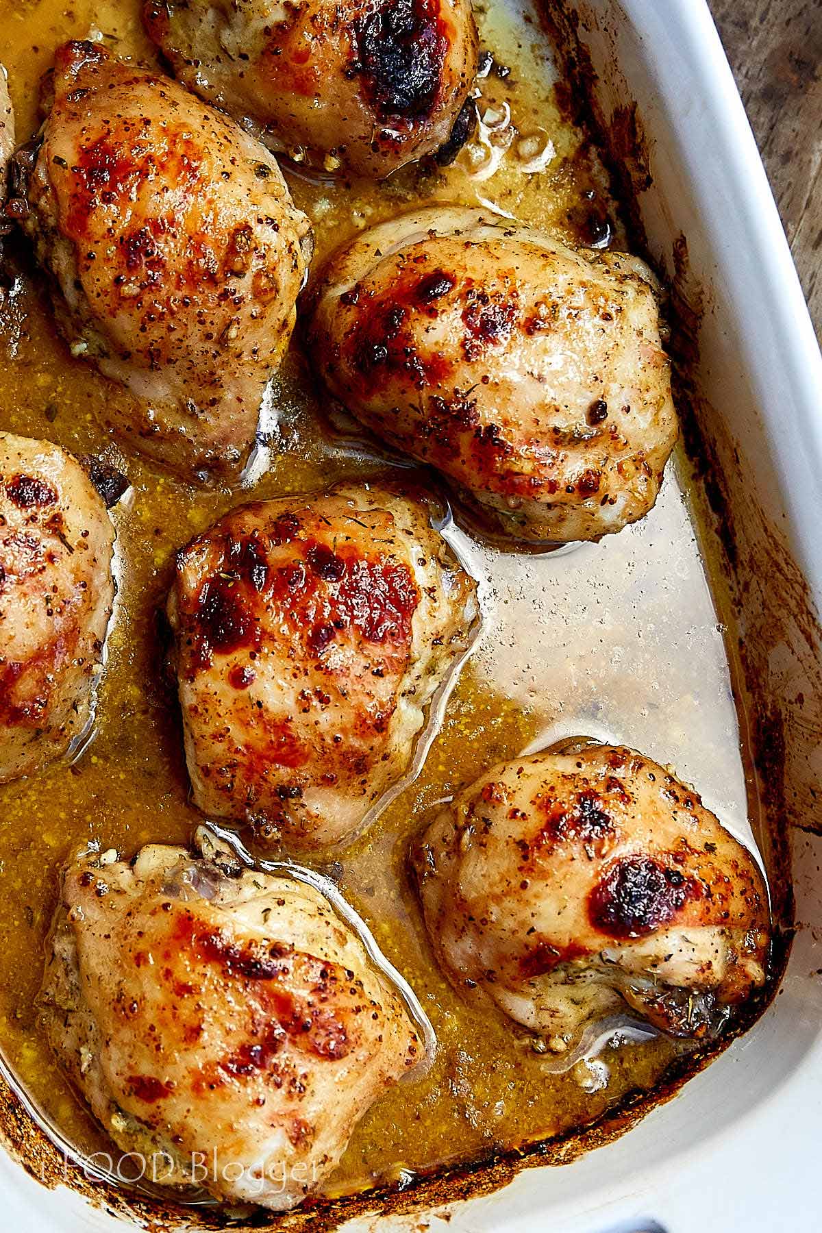 Close up of hone mustard chicken pieces in pan juices.