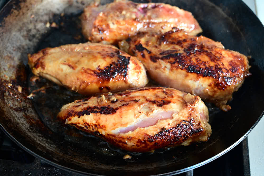 Pan-searing chicken breasts in a cast iron pan.