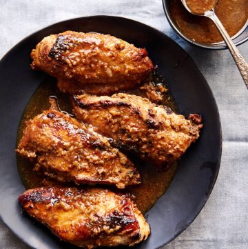 Juicy, browned chicken breasts on a black serving plate.