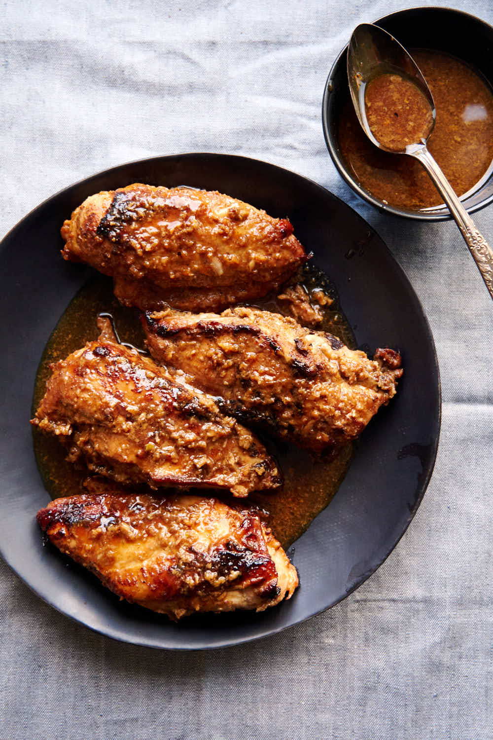 Juicy, browned chicken breasts on a black serving plate.