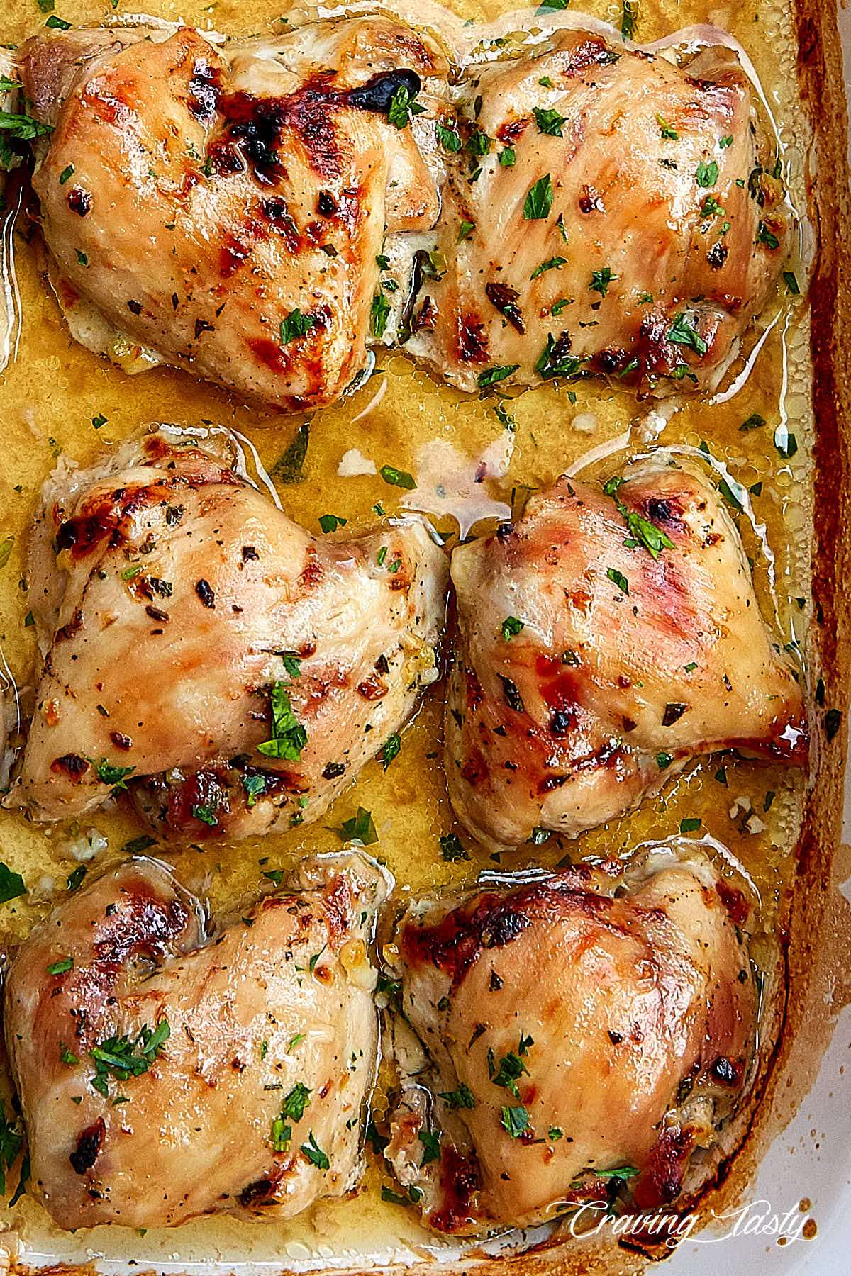 Cooked skinless boneless chicken thighs in a large white baking dish.