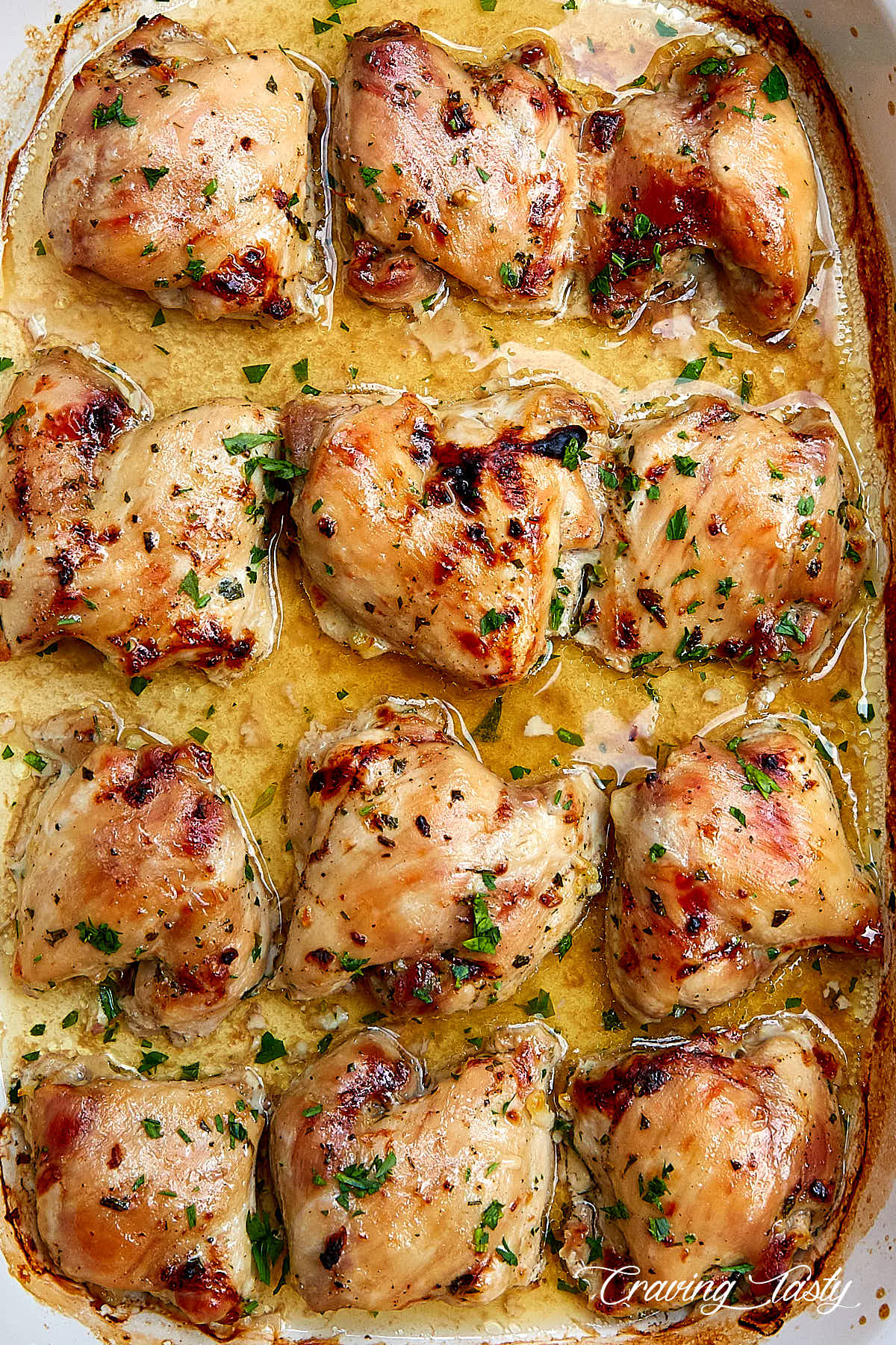 Top down view of nicely browned, moist skinless chicken thighs in a baking dish with pan juices.