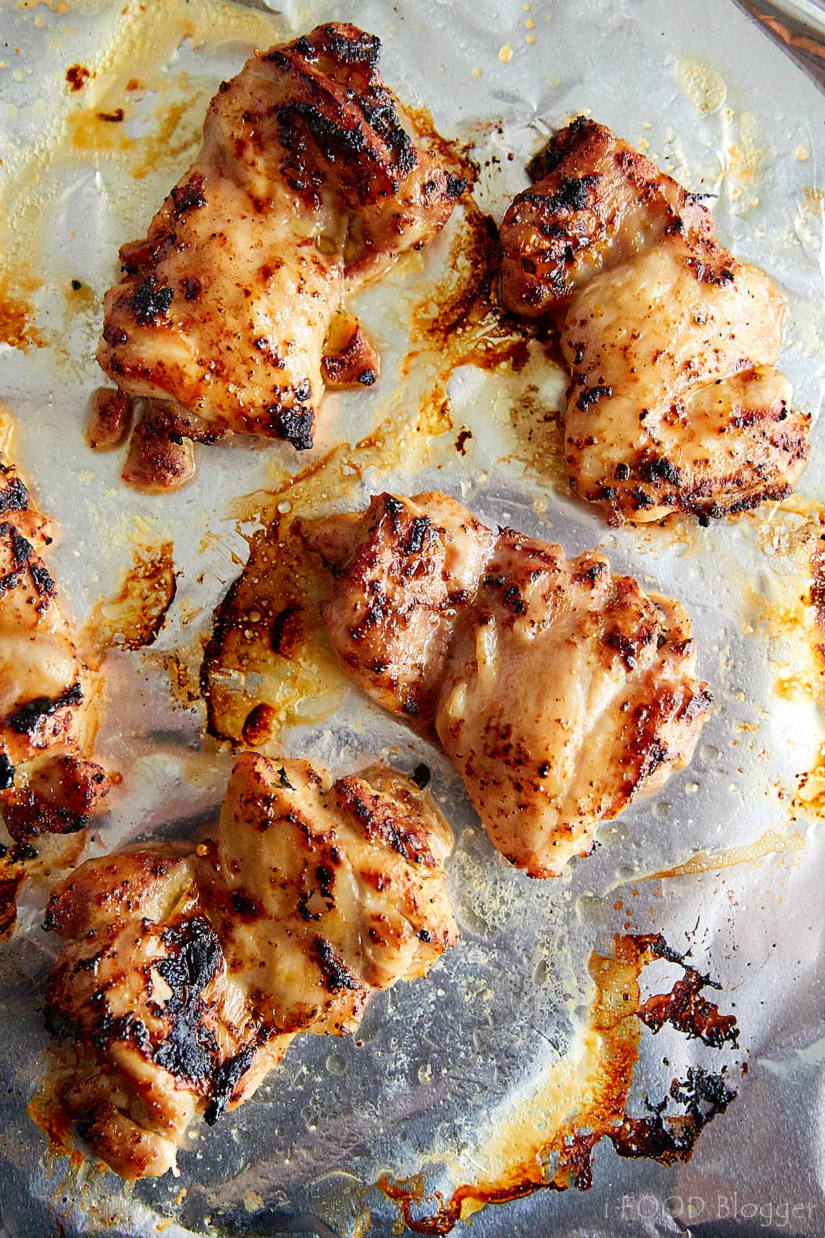 Top down view of nicely browned broiled chicken thighs on a baking sheet.