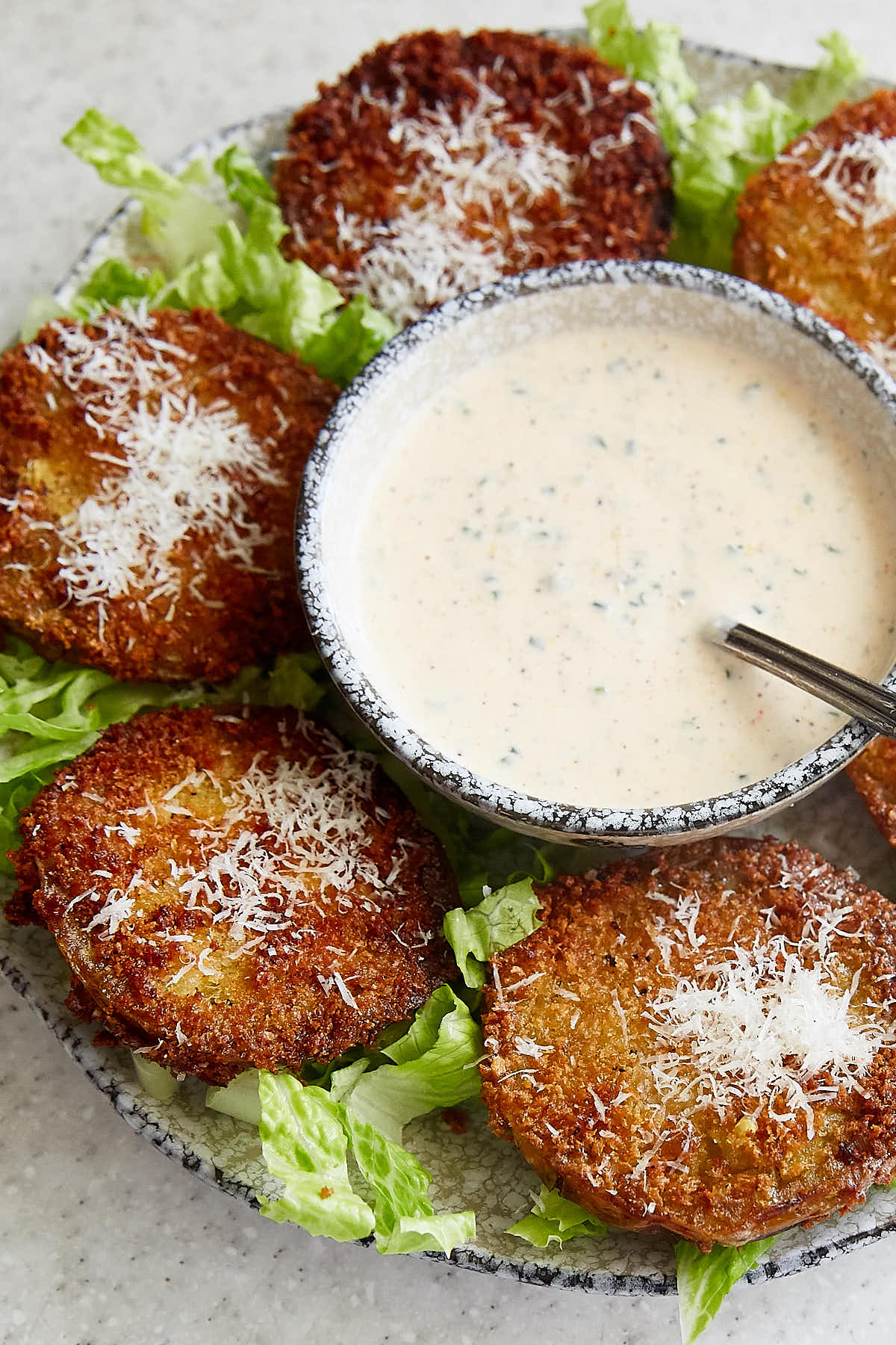 A bowl of ranch dressing next to fried green tomatoes.