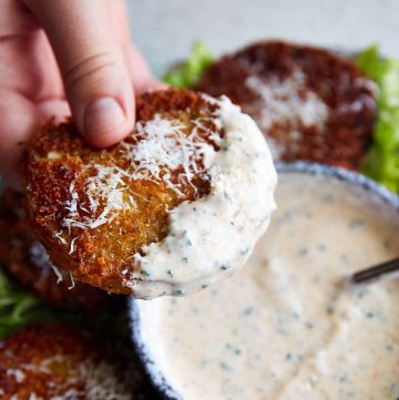 A fried green tomato dipped in ranch sauce.
