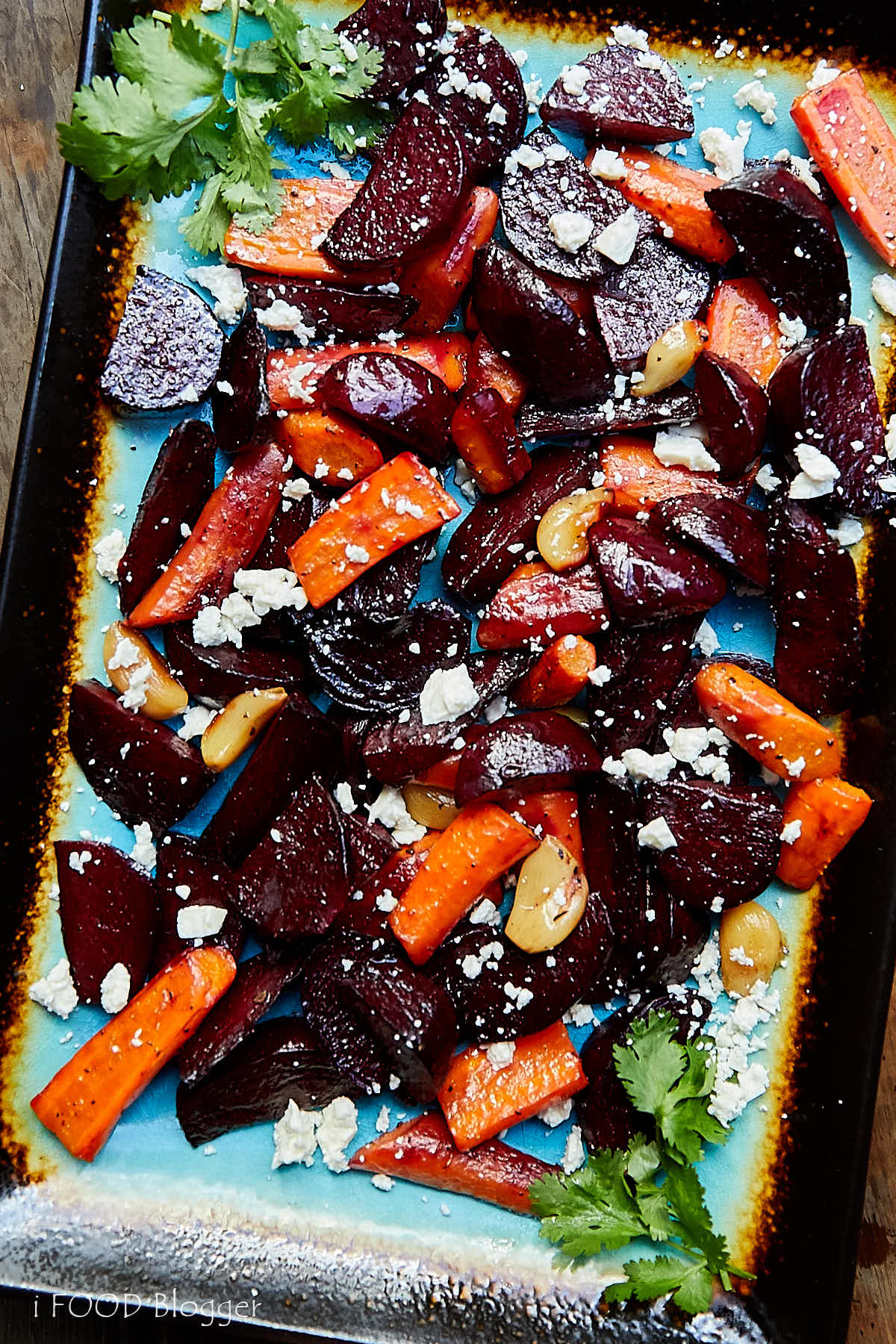 Roasted Beets and Carrots with Feta on a blue serving platter with black rims.